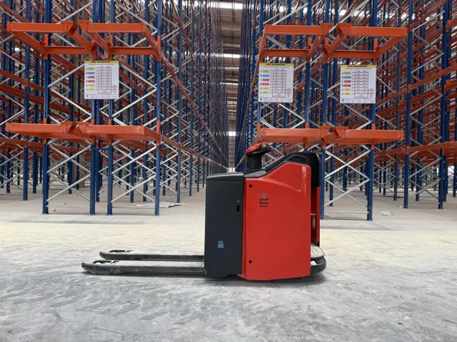 Red electric pallet truck in a pallet racking aisle