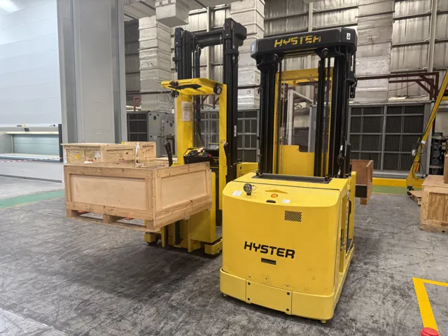 Two Hyster order pickers carrying wooden crates on their forks