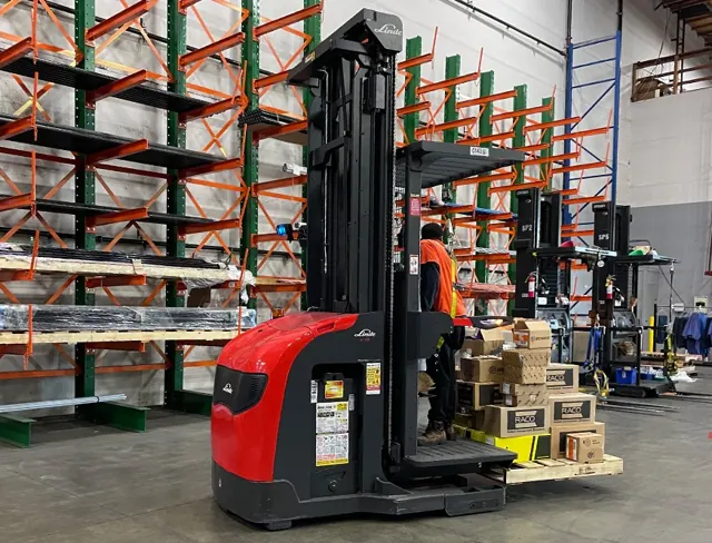 Red Linde order picker with an operator beside cantilever racking