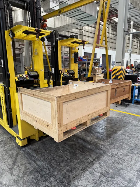 Order picker lifting a wooden crate in an industrial building