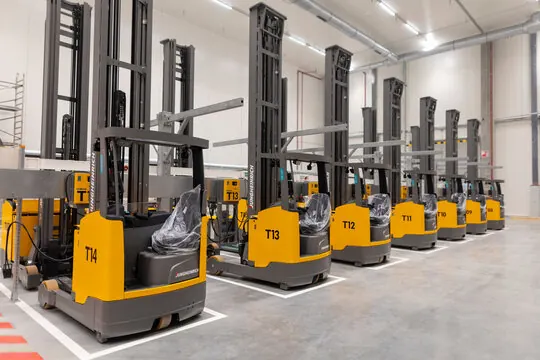 Row of yellow reach trucks parked in a warehouse