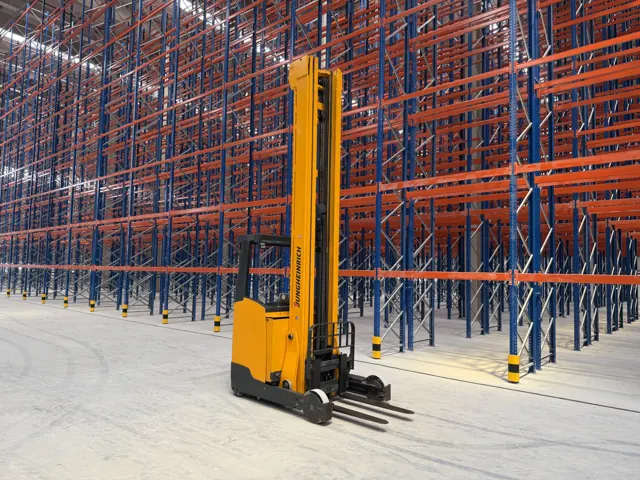 Yellow electric reach truck between tall pallet racking