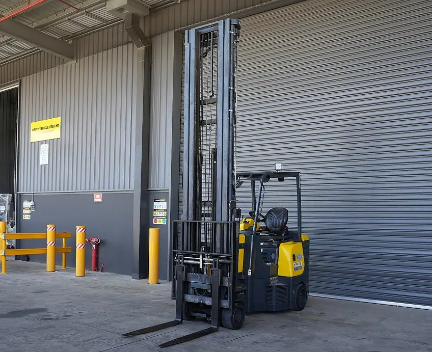 Aisle-Master articulated forklift with a high mast at a loading bay door