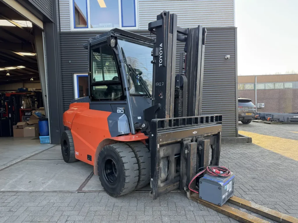 Toyota electric forklift with a battery charger standing on its forks